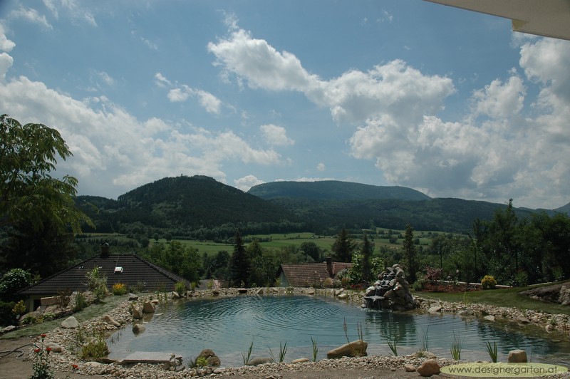 Swimming pond with a boulder waterfall and a mountain view, Austria